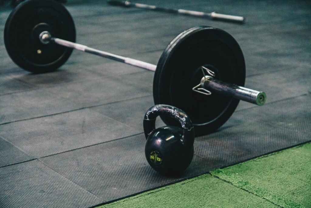 Barbell and kettlebell on gym floor, ideal for fitness and strength training themes.